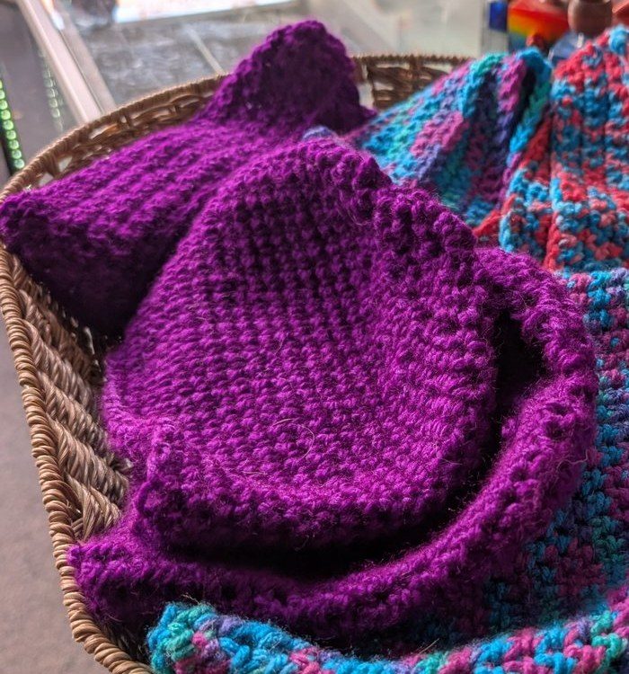 Deep purple crochet cat-ear beanie in a basket
