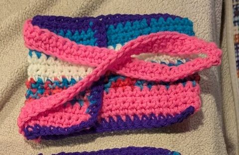 Pink, purple and teal crochet purse with a long pink strap
