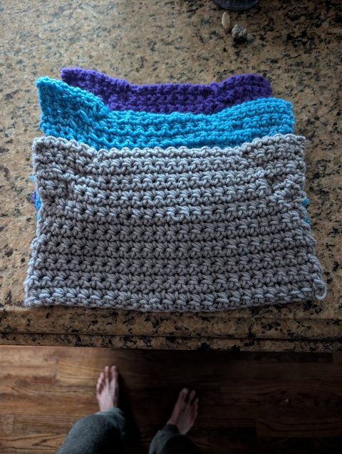 Stack of crochet cat-ear beanies in shades of blue
