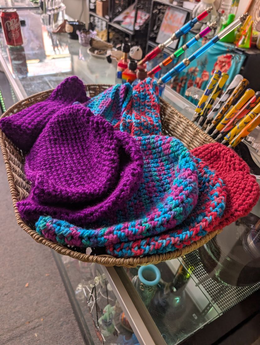 A basket of handmade crochet hats in purple, pink and blue